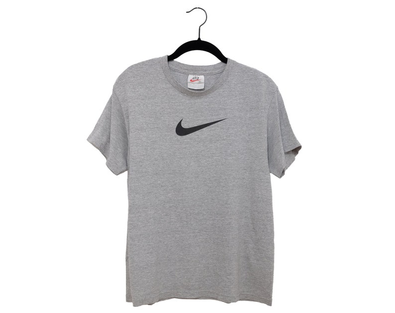 May include: A gray t-shirt with a black Nike swoosh logo.