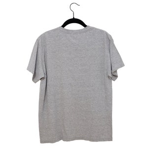May include: A plain gray t-shirt hanging on a black hanger against a white background.