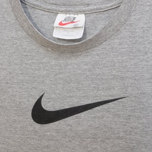 May include: Gray t-shirt with a black Nike swoosh logo. The tag says "NIKE" and "XL".