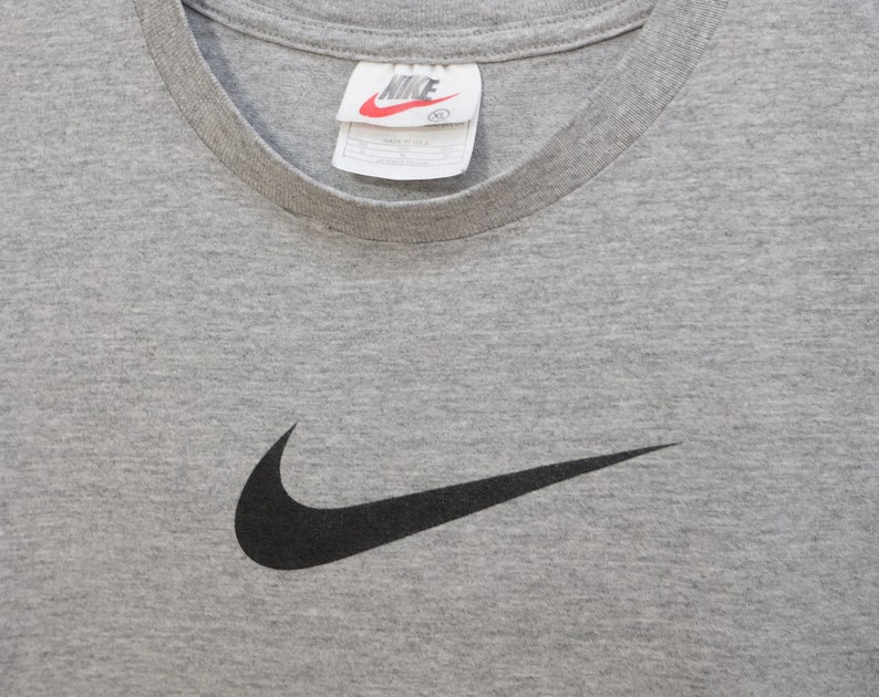 May include: Gray t-shirt with a black Nike swoosh logo. The tag says "NIKE" and "XL".