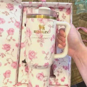 May include: A white ceramic mug with a black handle and the text "But First, Coffee" in a black, handwritten-style font. The mug is on a white surface.