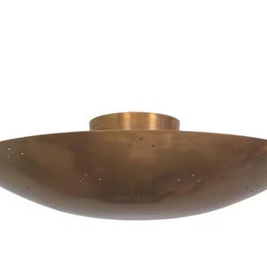 May include: A brass-coloured, bowl-shaped ceiling light fitting. The fitting has a wide, shallow bowl with a cylindrical centre and small, evenly spaced holes near the bottom edge. The light is suspended from the ceiling.