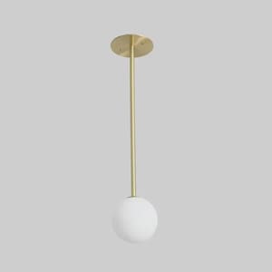 May include: A contemporary pendant light with a brass finish. It has a circular ceiling plate, a thin rod, and a spherical white glass shade. The design is minimalist and elegant, suitable for various interior styles. The rod's length is approximately 30 cm.