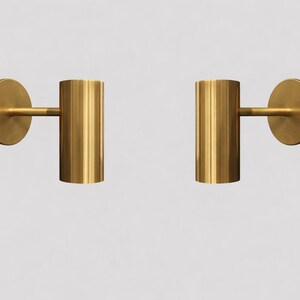 Peut inclure: Deux appliques murales dorées assorties. Chaque applique comprend une base circulaire, un bras horizontal et un luminaire cylindrique. Les luminaires sont en métal brillant.