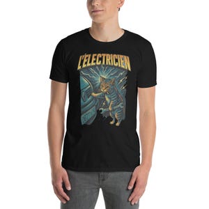 May include: Black t-shirt featuring a cartoon cat with a wrench, working on a car. The design includes the text "L'ELECTRICIEN" in yellow and blue, with lightning bolts. The car has a license plate with the number "0677Y74".