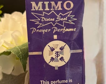 May include: A purple box of "EDIDI MIMO Prayer Perfume" with silver lettering and a circular emblem. The text includes "Divine Seal" and "100% Divinely Created & Consecrated." The box contains 125ml of perfume.