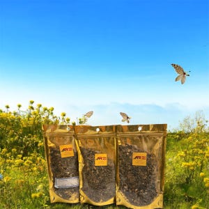May include: Three gold-coloured, resealable pouches filled with dried herbs or botanicals, each with a small, rectangular label. The pouches are set against a backdrop of a field of yellow flowers, butterflies, and a blue sky.