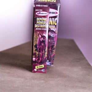 May include: Two boxes of incense sticks. The boxes are primarily red and purple, with the words "DEMONIC POWERS DESTROYER" and "INCENSE STICKS" printed on them. The boxes also feature an illustration of a figure in a robe.