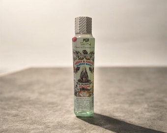 May include: A clear glass bottle of Florida Water cologne with a patterned label. The label features text including "Mercy & Favor Florida Water" and "All Purpose Cologne". The bottle has a white and gray patterned cap.
