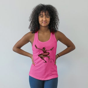 May include: A bright pink tank top featuring a graphic of a woman in a dancing pose. The illustration is in shades of brown and red, with the text "The Universal with Nadia" printed below. The tank top is sleeveless.