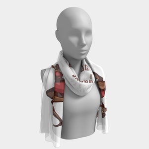 May include: A white scarf featuring a brown and red illustration of a person in a dancing pose. The scarf has the text "JAG" and "2000" printed on it. The scarf is draped around a mannequin's neck.