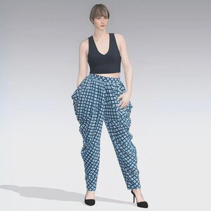 Peut inclure: Une femme porte un crop top noir et un pantalon bleu à motifs. Le pantalon présente un motif carré blanc sur fond bleu. Elle porte également des talons hauts noirs.