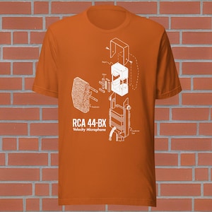 May include: Orange t-shirt with a white diagram of an RCA 44-BX Velocity Microphone. The diagram shows the microphone's components with labels. The shirt is made of a soft material. The design is printed on the front.