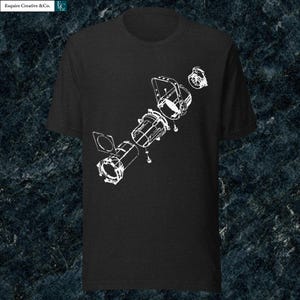 May include: Black t-shirt with a white technical diagram of a disassembled device. The illustration shows various components, including cylindrical and rectangular shapes, with connecting lines and screws. The shirt has a crew neck and short sleeves.