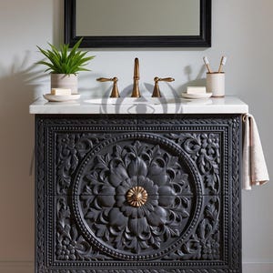 Puede incluir: Un mueble de baño gris oscuro con intrincadas tallas florales. Tiene una encimera blanca, grifos de latón y patas doradas. Un espejo cuelga encima, con una pequeña planta y un jabonera. Aproximadamente 90 cm de ancho.