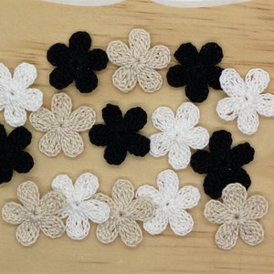 May include: Assortment of crocheted flower embellishments in black, white, and beige. The flowers are approximately 1 inch in diameter.