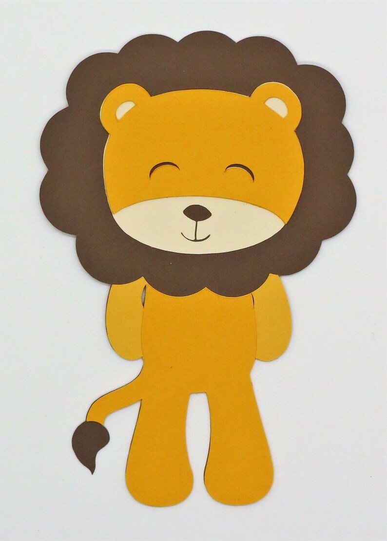 Puede incluir: Un recorte de papel marr&oacute;n y amarillo de un le&oacute;n con una melena marr&oacute;n. El le&oacute;n tiene una cara sonriente con los ojos cerrados y una peque&ntilde;a nariz negra.