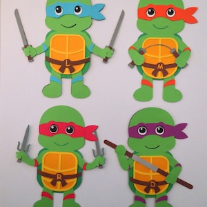 May include: Four Teenage Mutant Ninja Turtles paper cutouts. Each turtle is green with a different colored mask and weapon. The turtles are wearing brown belts with a letter on each belt: L, M, R, and D.