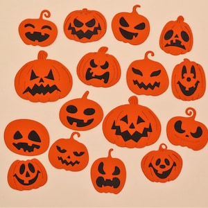 May include: A collection of 14 orange paper cut-out pumpkins with black facial features. The pumpkins are arranged in a random pattern on a white background.