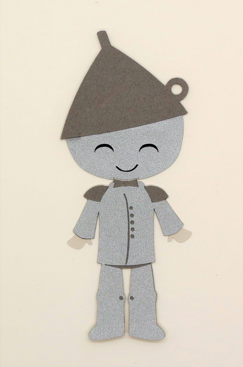 Puede incluir: Un recorte de papel plateado y marr&oacute;n del Hombre de Hojalata del Mago de Oz. El Hombre de Hojalata est&aacute; sonriendo y lleva un sombrero marr&oacute;n.