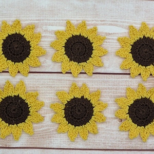 May include: Six crocheted sunflower embellishments in yellow and brown. The sunflowers are arranged in two rows of three.