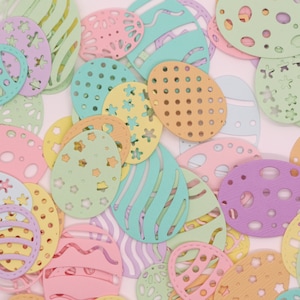 May include: Assortment of pastel colored paper Easter eggs with various cut-out designs. The eggs are in a variety of shapes and sizes, including some with polka dots, stripes, and stars.