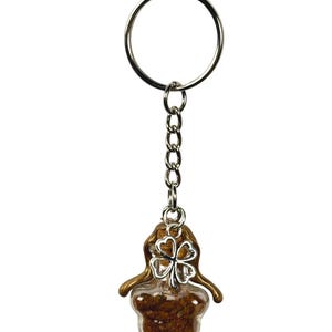 May include: A keychain with a silver ring and chain. The charm is a clear, star-shaped container filled with brown material, topped with a brown and silver clover design. The charm is approximately 1.5 inches in length.