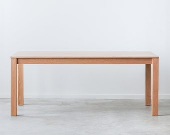 May include: A light wood rectangular dining table with four legs. The table is on a gray concrete floor.