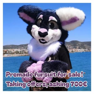 Puede incluir: Un disfraz de piel con cabeza y patas en negro, blanco y morado. La cabeza tiene orejas grandes y una expresión amigable. El texto "Premade fursuit for sale! Taking offers, asking 700€" se muestra en morado.