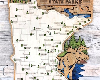 May include: Wooden map of Minnesota State Parks. The map is laser-cut with a light wood finish and features the state outline, park names, and a moose illustration. The text "MINNESOTA STATE PARKS" is at the top.