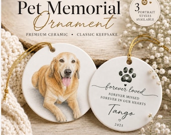 May include: Two round white ceramic ornaments with gold hanging strings. One ornament features a portrait of a golden-colored dog. The other ornament displays a black paw print, the text forever loved, forever missed, forever in our hearts, Tango, and 2025.