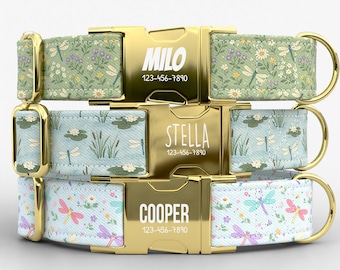 May include: Three personalized dog collars with gold-colored buckles. The top collar is green with a floral and dragonfly pattern, the middle is light blue with a pond design, and the bottom is light blue with dragonflies and flowers. Each buckle has a name and phone number.