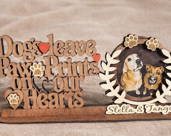 May include: Wooden dog memorial with the phrase "Dogs leave paw prints on our hearts." Features a photo of two dogs, Stella and Tango, within a decorative frame. Includes paw print and heart accents.