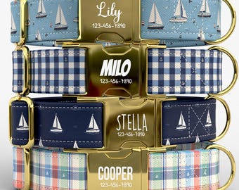 May include: Four stacked pet collars with gold-tone metal buckles. The top collar is light blue with sailboats, the second is blue and white gingham with anchors, the third is navy with sailboats, and the bottom is a multi-colored plaid pattern.