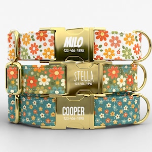 May include: Three personalized dog collars with floral patterns. The collars feature gold-colored metal buckles engraved with names and phone numbers. The floral patterns include orange, yellow, and green flowers on white, green, and teal backgrounds.