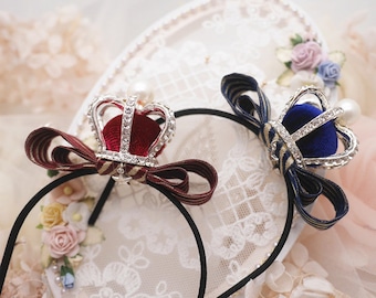 May include: Two hair clips with jeweled crowns and velvet bows. One bow is red and the other is blue.