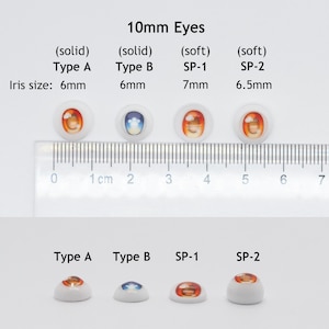 May include: Four pairs of 10mm doll eyes, two solid and two soft. The solid eyes are 6mm in diameter and the soft eyes are 7mm and 6.5mm in diameter. The eyes are arranged in two rows, with the solid eyes in the top row and the soft eyes in the bottom row. The eyes are all different colors and designs.