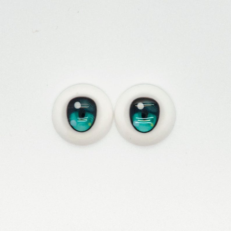 May include: A pair of blue and green doll eyes with white sclera. The eyes are designed for doll making and crafting.