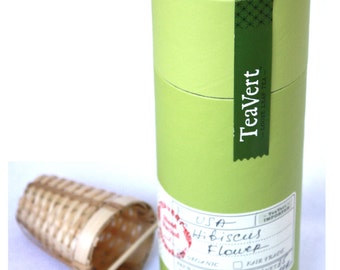 May include: Green cardboard tube with a label that says "TeaVert - Loose Leaf Tea" and a sticker that says "Hand Packed" and "USA Hibiscus Flower" with a red stamp that says "Organic" and "Fair Trade".