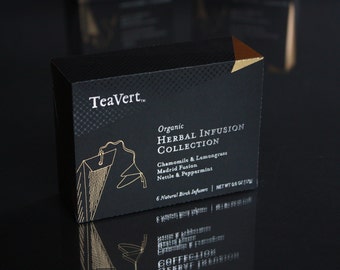 May include: A black box with gold lettering that reads "TeaVert Organic Herbal Infusion Collection" and lists the flavors: Chamomile & Lemongrass, Madrid Fusion, Nettle & Peppermint. The box contains 6 natural birch infusers and has a net weight of 0.8 oz (22 g).
