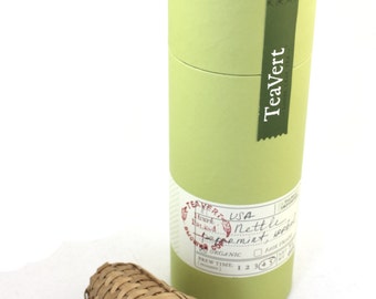 May include: A green cardboard tube with a label that reads "Teavert" and "USA Nettle Peppermint Tea" with a bamboo tea infuser next to it.
