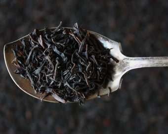 May include: A silver spoon filled with loose leaf black tea.