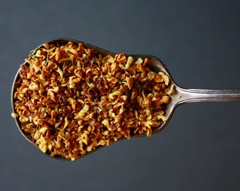 May include: A silver spoon filled with dried orange blossoms, a common ingredient in teas and other culinary creations.