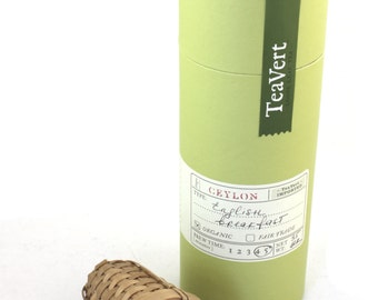 May include: A green cylindrical box with a white label that reads "TeaVert - Ceylon English Breakfast - Organic - Fair Trade - Net Wt. 31g" and a bamboo tea infuser with a wooden handle.