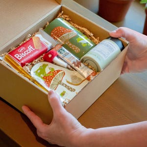 Hands opening the Frog Mushroom Mug Gift Box revealing neatly packed cozy contents designed for heartfelt gifting and woodland themed joy perfect for birthdays self care or thoughtful Christmas presents for nature lovers
