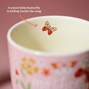 A pink mug with a small, colorful butterfly design on it.
