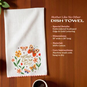 a white dish towel with a colorful butterfly design and the phrase "mother like no other" printed on it, placed on a wooden surface next to two cups of coffee.