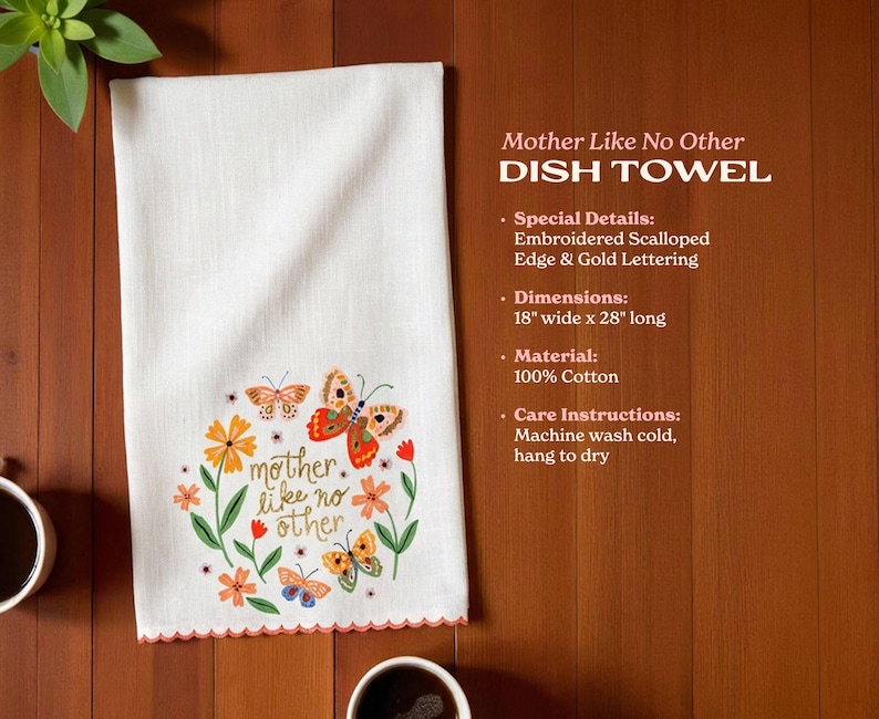 a white dish towel with a colorful butterfly design and the phrase "mother like no other" printed on it, placed on a wooden surface next to two cups of coffee.