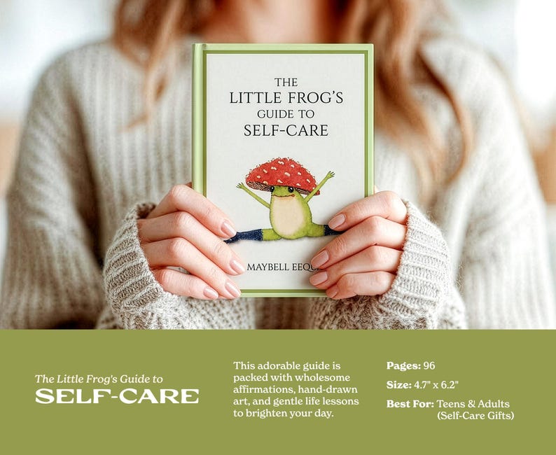 A person holding a hardcover copy of 'The Little Frog's Guide to Self-Care' book featuring a whimsical illustration of a frog wearing a mushroom cap. Text details the book's size, pages, and uplifting illustrations.