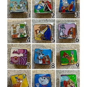May include: A collection of twelve square, silver-toned metal charms with colorful enamel designs. Each charm features a different cartoon character, including rabbits, Alice in Wonderland, and characters from Beauty and the Beast.